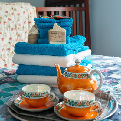 Soap, folded towels and a tea set sit on a bed.